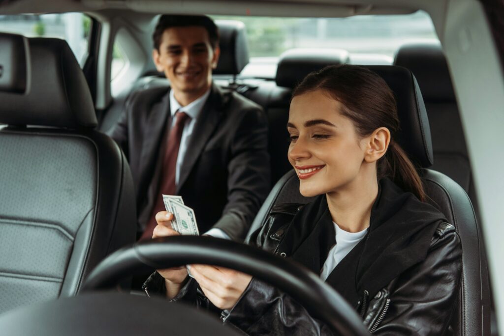 Smiling taxi driver holding cash with businessman at background